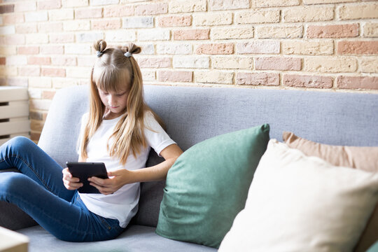 Teenage schoolgirl doing homework with digital tablet at home. A child using gadgets to study. Education and distance learning of children. Homeschooling during quarantine. Stay home fun.