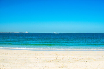 Fototapeta na wymiar Beautiful public beach with turquoise water and a white sand in Persian Gulf shoreline, Dubai.