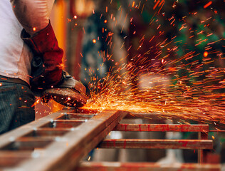 A close-up of a mechanic working with a grinder, sparks flying in gloves. Construction concept