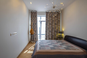 Contemporary interior of luxury bedroom in apartment. Cozy king-size bed. Front view of window.