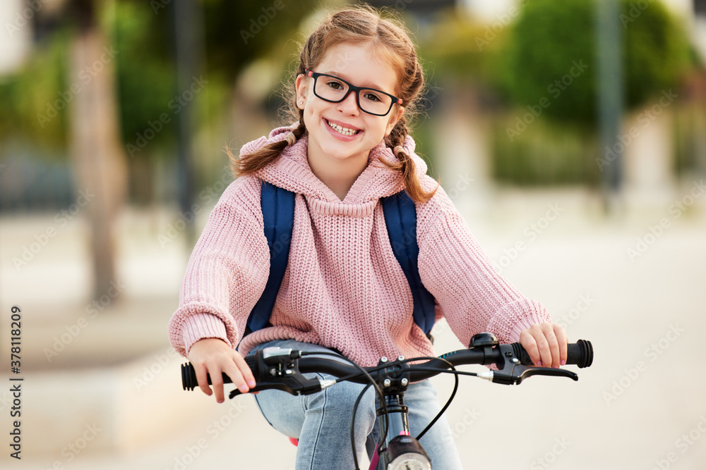 Wall mural funny girl goes to school on a bicycle.