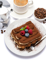 portion of Classic tiramisu dessert with raspberries and blueberries, cup of espresso and coffee maker isolated on white background with clipping path