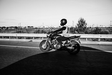 Man rides a motorcycle in the city.Motorcyclist riding a bike during the day on the road.Black and...
