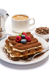 portion of Classic tiramisu dessert with raspberries and blueberries, cup of espresso and coffee maker isolated on white background with clipping path
