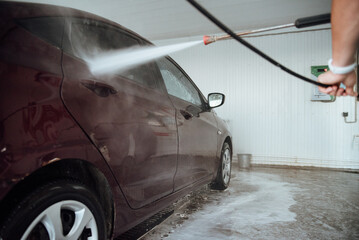 Shot of a man washing his car under high pressure water outdoors.