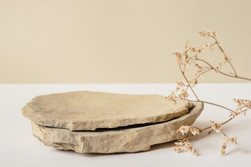 Background for cosmetic products of natural beige color. Stone podium and dry flower on a white...