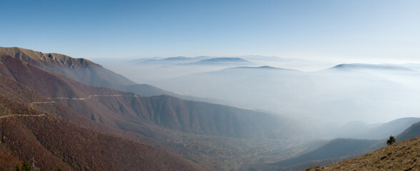 Scenic panoramic view from the mountain Vlasic, a valley filled with fog and peaks above the fog in autumn during a sunny day.