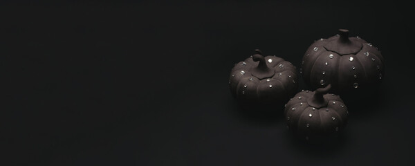 Ceramic pumpkins with rhinestones on a black background. Minimalistic background for autumn holidays with space for text.