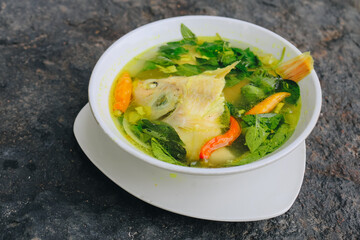 Gurame fish head soup or sup kepala ikan gurame with basil leaves, tomatoes, yellow curry, and...