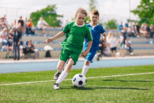 Young boys playing soccer game. Kids having fun in sport. Happy kids compete in football game. Running soccer players. Competition between players running and kicking football ball. Football school