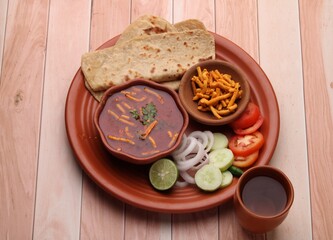 Obraz na płótnie Canvas Dhaba style Sev bhaji/sabzi/curry made in tomato curry with gathiya shev, served with chapati/ roti.