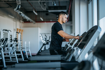 Fototapeta na wymiar Man running in machine treadmill at fitness gym.