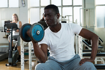 Fototapeta na wymiar Confident african man doing strength exercises with barbell in gym