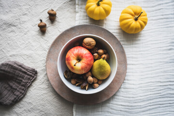 Herbstlich gedeckter Tisch mit Apfel, Birne und Nüssen in einer Schüssel. Thanksgiving, Draufsicht, gelbe Kürbisse.