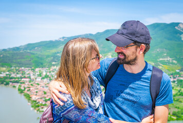 Close up of young couple hugging each other and smiles face to face with panoramic scenic view to green nature nd Mtkheta town in Georgia. Travel buddies relationship. concept of travel couples joy