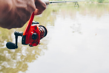 Close up of spinning with the fishing reel in the hand, fishing hook on the line with the bait in...
