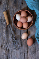 A BEATER AND AN EGGS BOWL READY TO BE COOKED ON OLD WOODEN TABLE. HEALTHY FOOD CONCEPT. TOP VIEW.