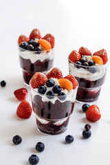 Festive cake for the birthday. Сakes with cream and berries. Desserts for adults and children on table. Festive cupcakes with chocolate and berries. Vertical photo.
