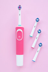 Electric toothbrush for cleaning teeth and round brush head on a pink background. Blue nozzles....