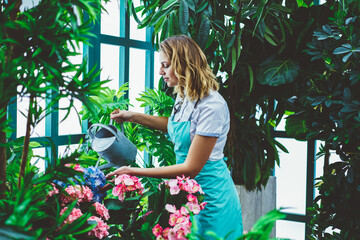 Young pensive woman watering flowers from can