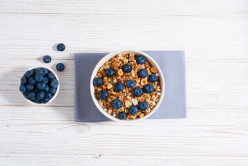 Fototapeta na wymiar Breakfast with granola and blueberry n the white table flatlay copy space. Healthy morning food