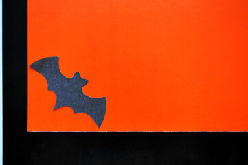 Black paper bat lies on orange-black background.
