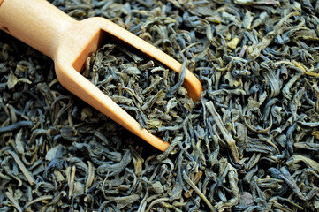 Wooden spoon lies in a heap of loose tea.