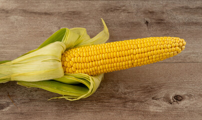corn cob on a wooden background. Corn is widely used in American cuisine. Zea mays is the second most marketable grain crop in the world. Corn protein contains a number of useful amino acids