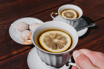 Tea party with delicious food and sweets. Ceramic white Cup and tea set. Hold a Cup of tea with lemon in your hand.
