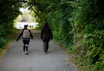une mère et sa fille marchent dans un parc pour aller à l'école