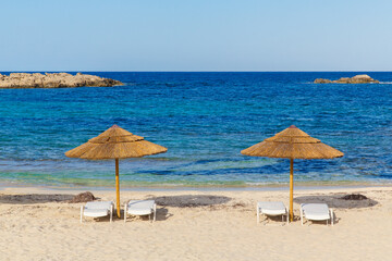 Sun beds and umbrellas on the sea coast of Formentera, Spain, the Mediterranean sea.