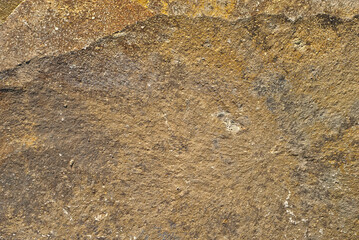 Flat stone texture. Part of a rock close up. Yellow stone with scratches and cracks.