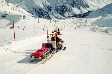 Snowmobile machine with sled and equipment riding fast hurry up driver to help injured skier or...