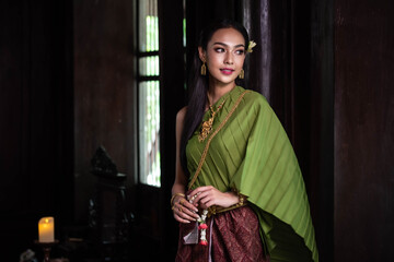 Portrait  of a beautiful woman in old Thai dress suit looks elegant and charming in Old antique Thai houses/Old Thai fashion model concept