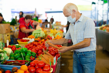 retired european man wearing medical mask protecting against virus buying tomatoes in market