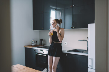 Positive lady drinking fresh juice and talking on mobile phone