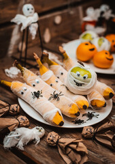 Sweet table with fruits and treats for Halloween. Decorations Apple bananas in the form of a mummy with eyes and Ghost. spiders and cockroaches