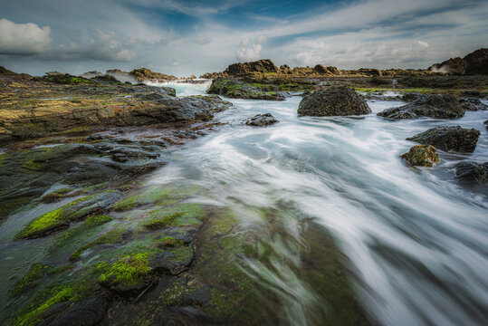 Sea wave flowing into rock beach view in long exposure shot