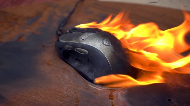 Burn the computer mouse. Close-up. Concept, a computer mouse caught fire from overload and intense work.