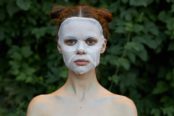 Nice girl white mask skin care green leaves in the background 