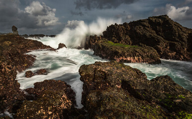 Sea water splashing on rock barrier in Siung beach, Java Island, Indonesia