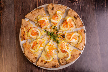 Pizza gourmet tagliata a spicchi con salmone, limone, mozzarella e prezzemolo