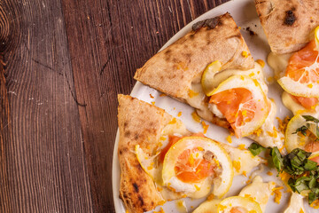 Pizza gourmet tagliata a spicchi con salmone, limone, mozzarella e prezzemolo