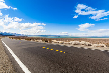 Route 120 is a seasonal road which is closed for part of the year, just opened there is still snow on the mountains, Mono Lake on the right of the road that winds through the Eastern Sierras.