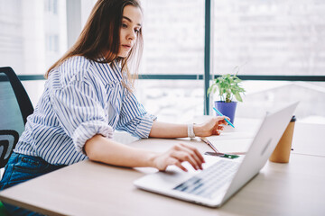 Skilled female student in smart casual wear using laptop application for making informative web research for creating university course work, Caucasian woman browsing wireless internet page