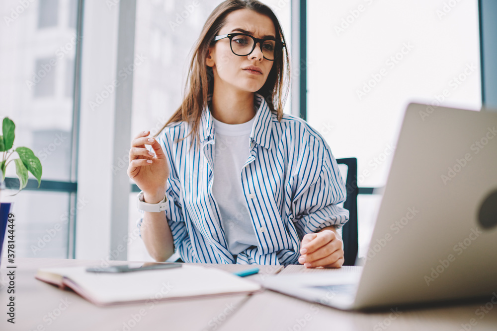 Poster puzzled female trainee in optical eyewear for vision correction watching tutorial webinar during net