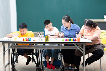 asian group of disabled kids or autism child learning and painting at paper with teacher helping in classroom