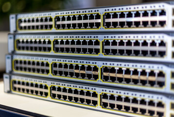 A stack of network switches with empty ports exposed just removed from a server cabinet in an office.