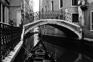 Fototapeta premium Venetian foreshortening in black and white with a typical bridge crossing a canal seen from a gondola