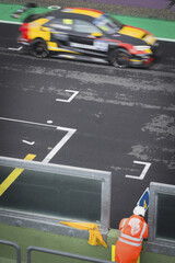 Racing car run fast in a blurred motion on racing track with sport crew man in the foreground